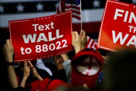 Trump supporters wave signage in favor of a border wall and Make America Great Again hats at the President's rally Monday.