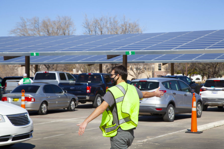 A man directs traffic into the green lanes for COVID-19 vaccination at NMSU.