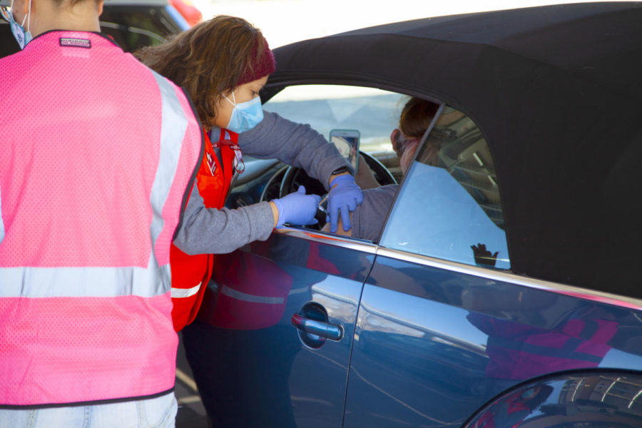 A woman films herself receiving a dose of the Pfizer COVID-19 vaccine in the red lanes of NMSU's vaccination site. The red lanes are reserved for faculty and staff members. 