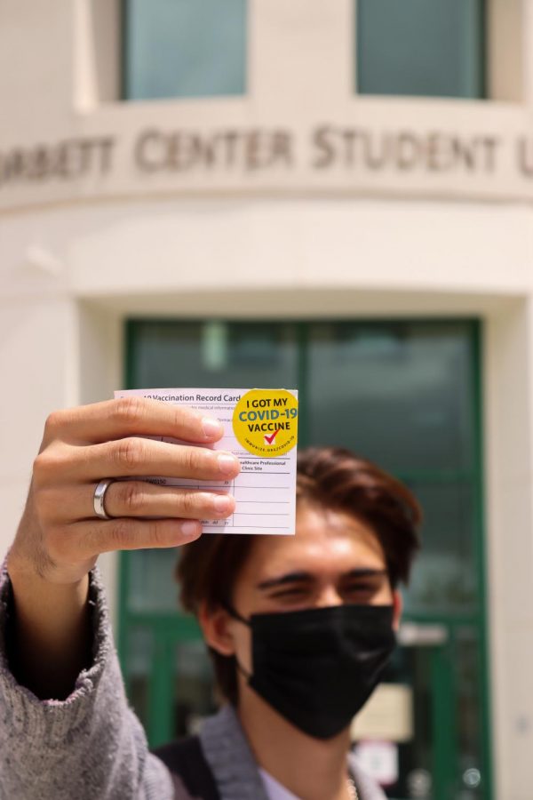 NMSU student show cases vaccination card.
