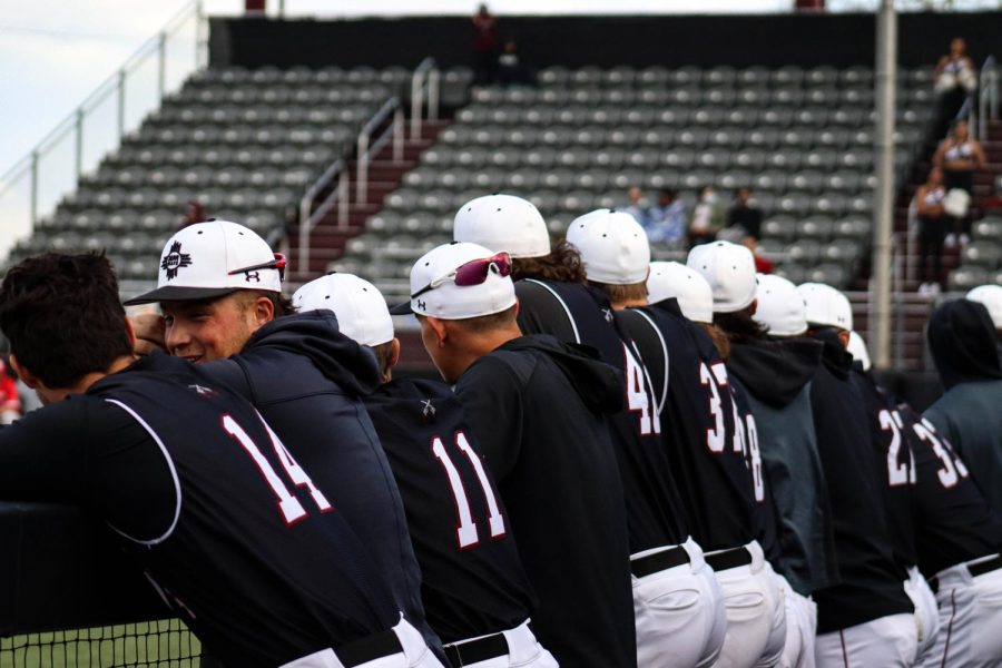 New Mexico State University baseball team watching their team warm up for the game.