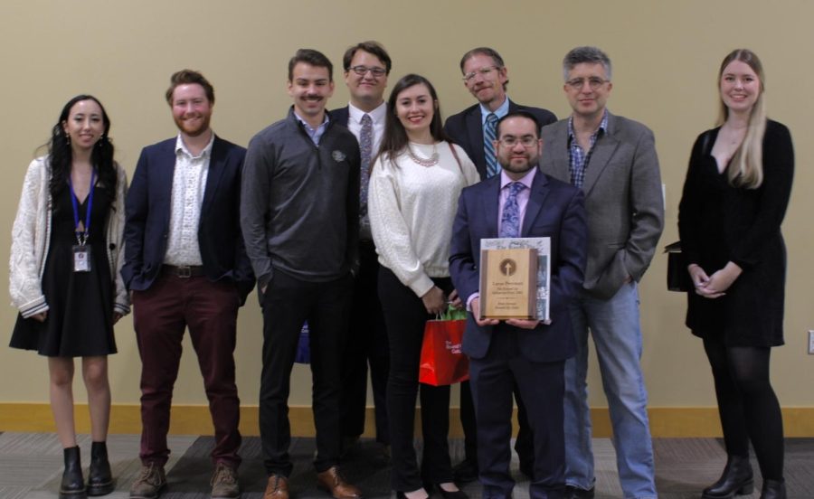 The sun new staff in a group photo with Lucas Peerman recognition presenting the award/plaque.