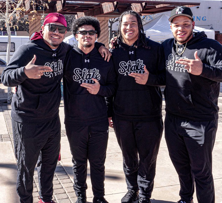 Four New Mexico State University football players pose with guns up in the  downtown plaza. Photo taken Jan. 21, 2023.
