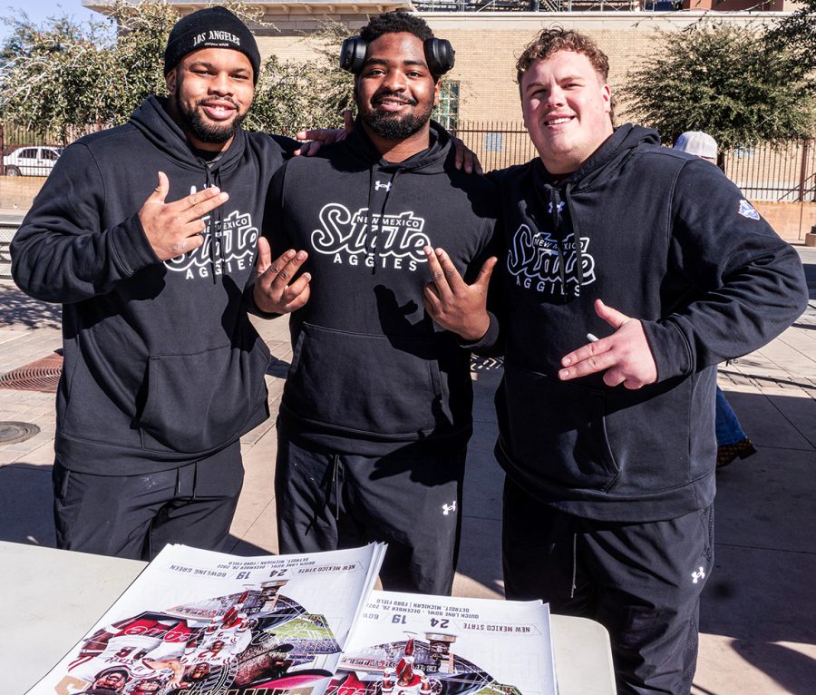 Three NMSU football players signing autographs for fans. (From left to right (Sterling Webb, Deven Dyer and Canaan Yarro.) Photos taken on Jan. 21, 2023.