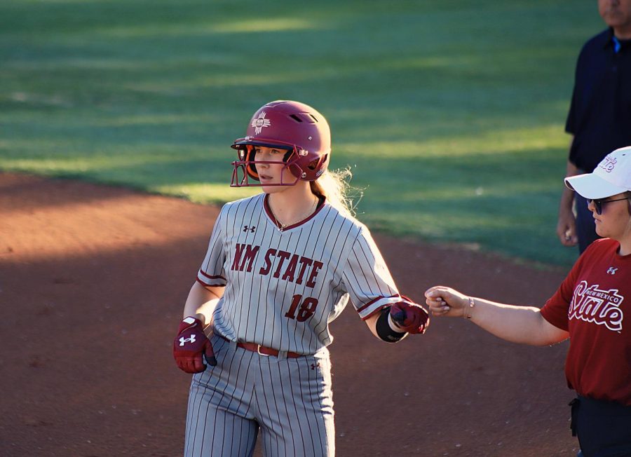 Infielder Kristen Boyd gives a fist bump to a NMSU softball staff member after getting first base. Mar. 4, 2023.