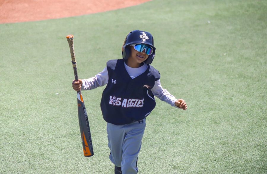 The NMSU batter boy runs with joy towards the dugout to return a players bat. April 16, 2023.
