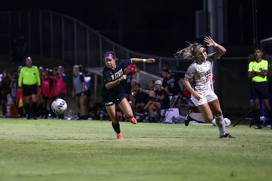 NMSU’s Janae Shaklee rushes to the ball with WKU’s Kendall Wade close behind. Sept. 26, 2024.