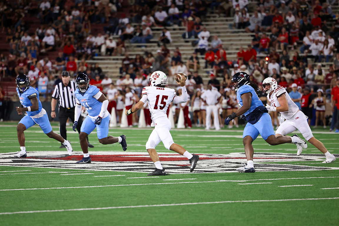 NMSU starting quarterback Parker Awad (No. 15) makes a pass midfield at Aggie Memorial Stadium surrounded by the Liberty Flame defense. Sept. 7, 2024.