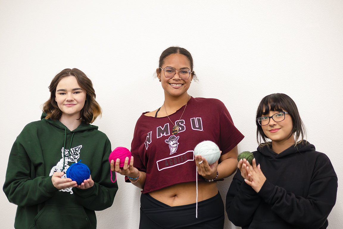 Crochet Cuties officers hold up balls of yarn, listed left to right: Megan Essenmacher (communications officer), Kendra Sarabia (secretary), Zoey Montoya (president). Feb. 19, 2025. 