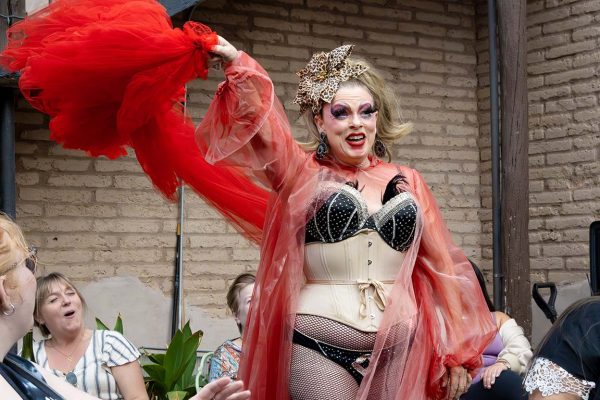 A Draglesque performer in a red flowing costume paired with a corset, fishnets, and an animal-print bow. Nov. 16, 2025. 