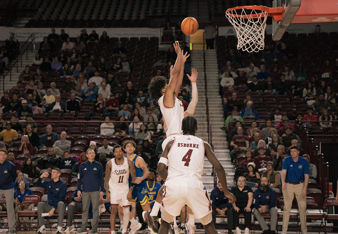 An NMSU basketball player jumps to contest a shot during the game against Delaware.