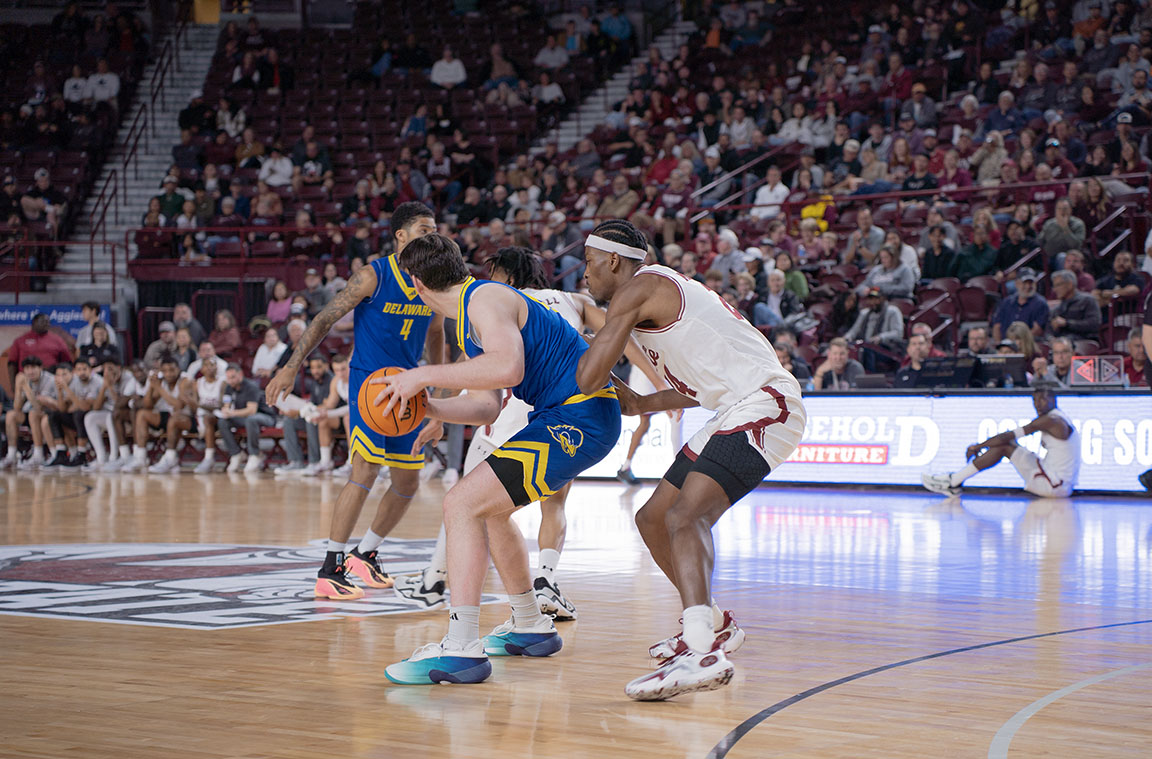NMSU #24 Cyr Malonga attempts to stop a Delaware player from scoring.