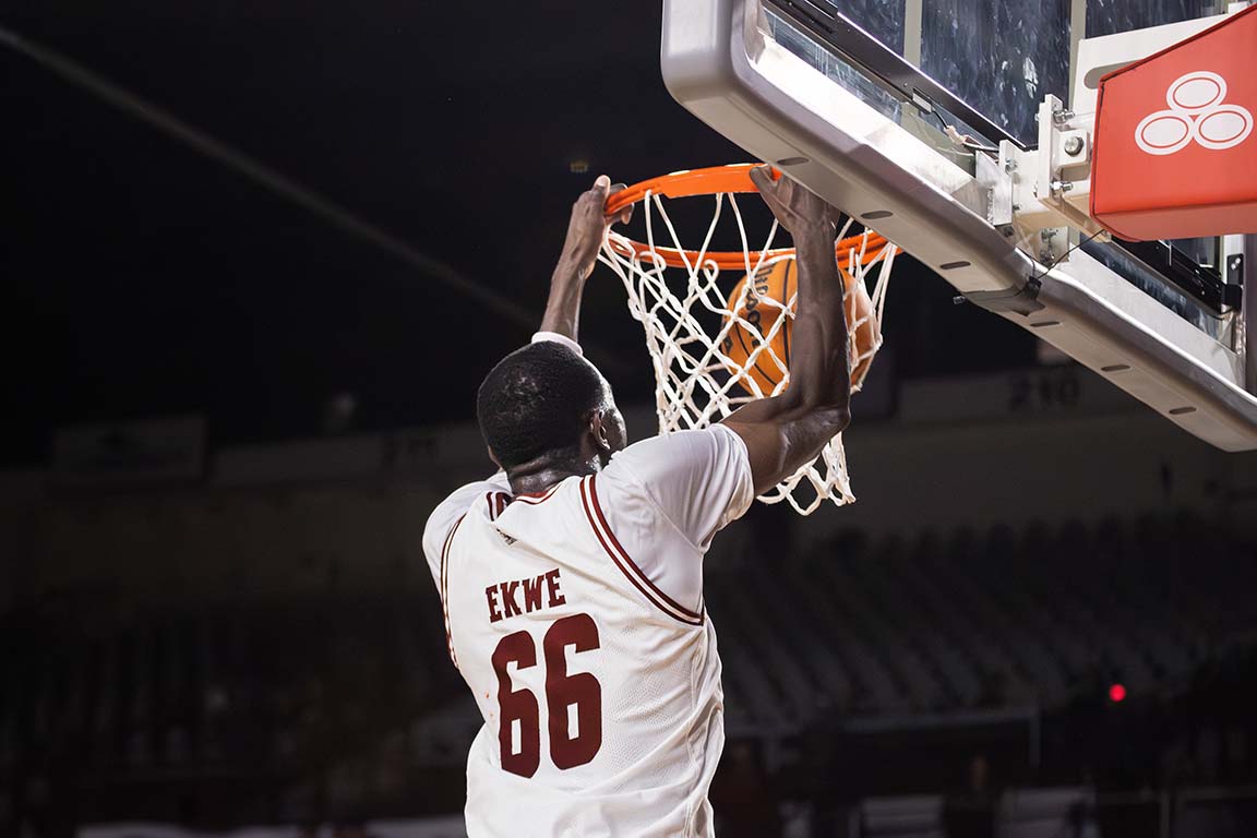 Center Augustine Ekwe (66) hangs onto the rim after completing a dunk for the Aggies against UTEP. Feb. 21, 2025