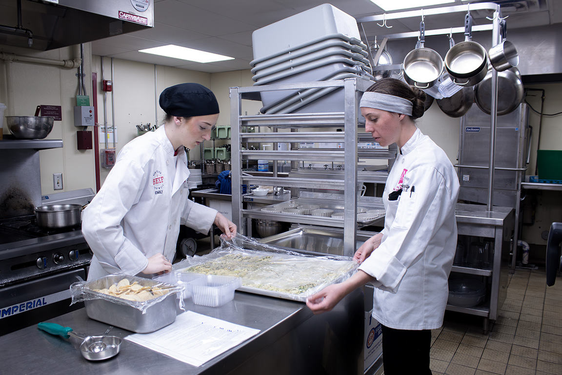 Two students of the School of Hotel, Restaurant, and Tourism Management collaborate to uncover a prepped sheet of battered vegetables. February 27, 2026.