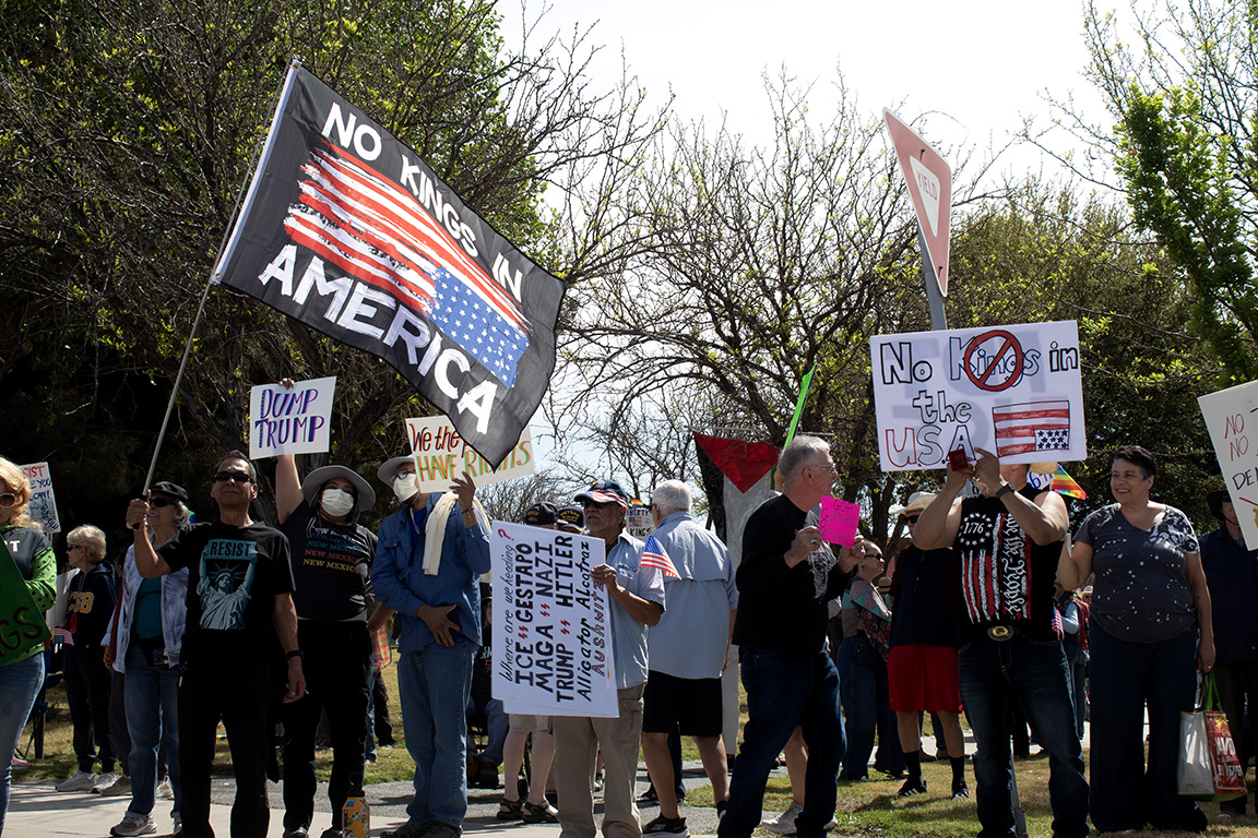 Dozens of protestors stand on N. Main Street and Picacho Avenue with a flag reading "No Kings in America." March 28, 2026.